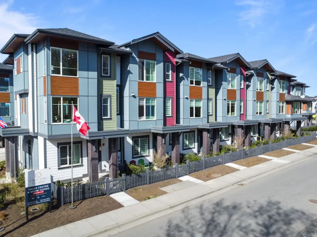 Completed Crofton detached townhomes street elevation with CROFTONLIVING.CA sales centre sign, Langley Willoughby