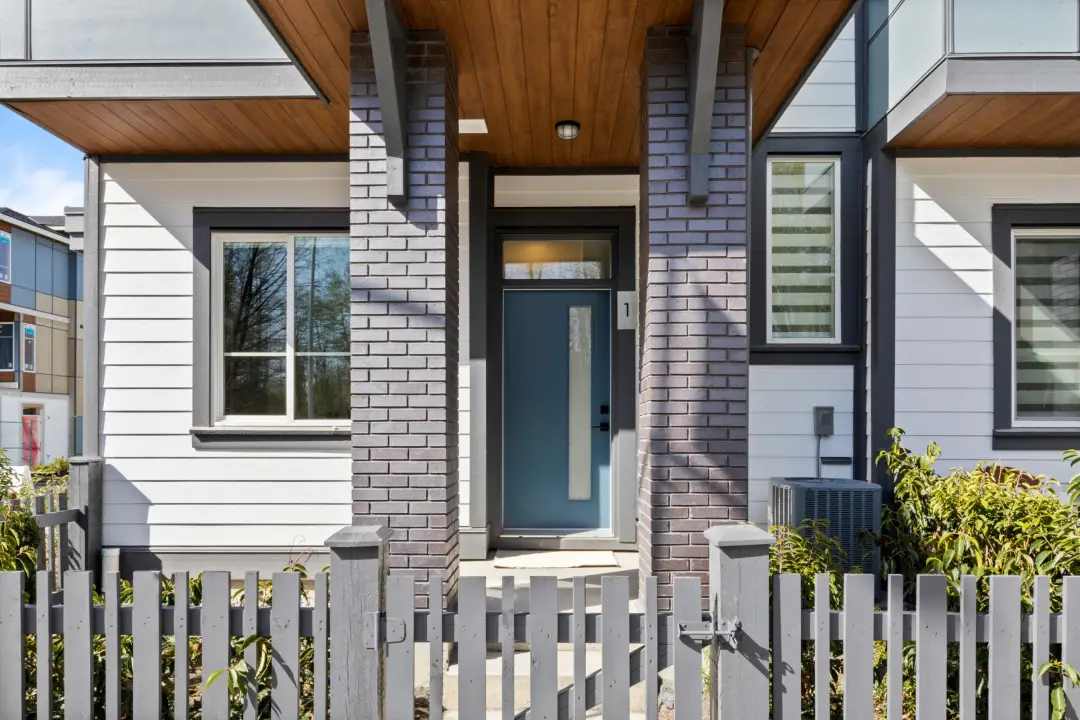 Crofton townhome unit 1 entrance with brick pillars, wood soffit, and porch lighting