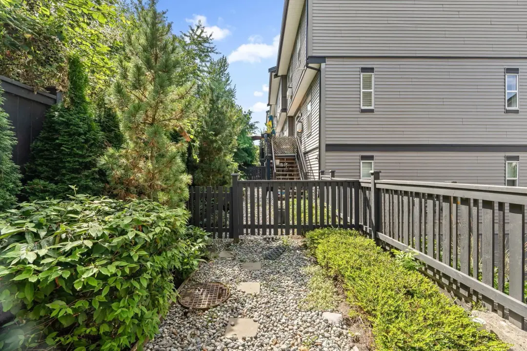 Frame backyard gravel patio with dark fence and townhome siding
