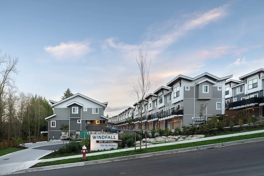 Dusk street view of Windfall townhomes with the WINDFALL monument sign in Maple Ridge