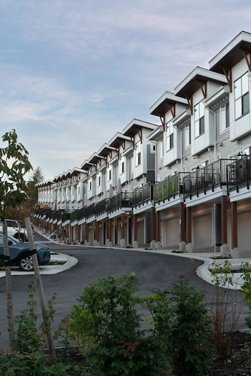 Curved street of Windfall townhomes with balcony lights in Maple Ridge