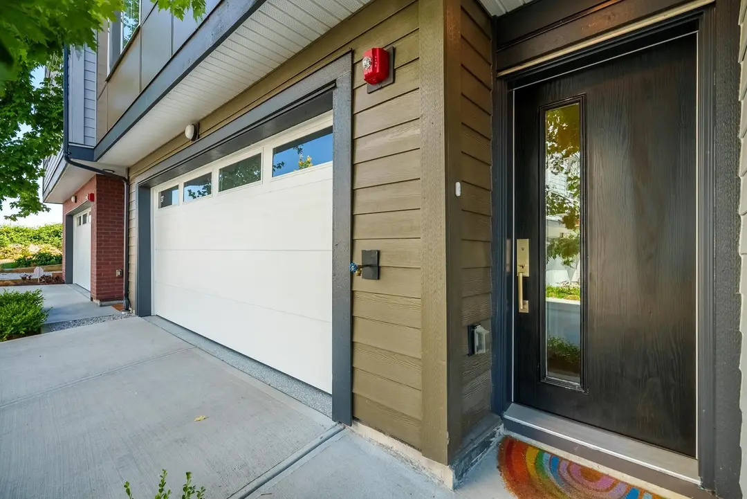 Parallel townhome garage and entry with exterior light, doorbell, and fire bell