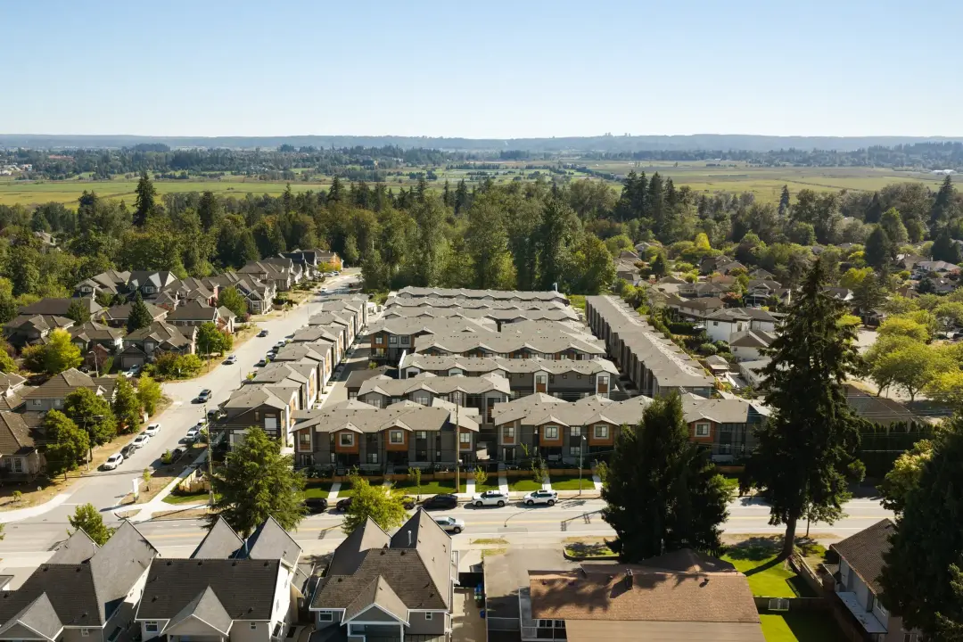 Drone aerial of Elwynn Green Surrey townhome complex beside trees and farmland