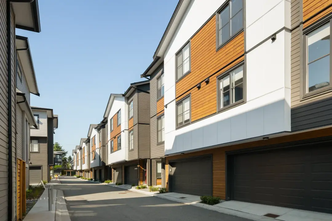 Driveway view of Elwynn Green townhomes with dark garage doors and contemporary cladding