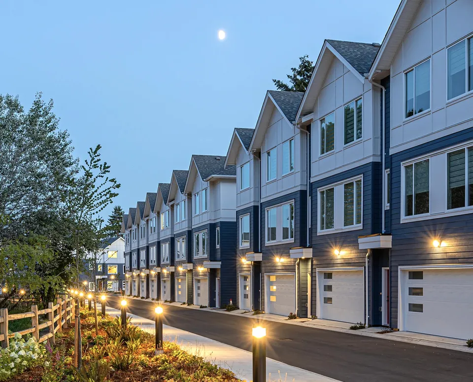 Park & Maven townhome row at dusk with garage wall sconces and bollard path lighting