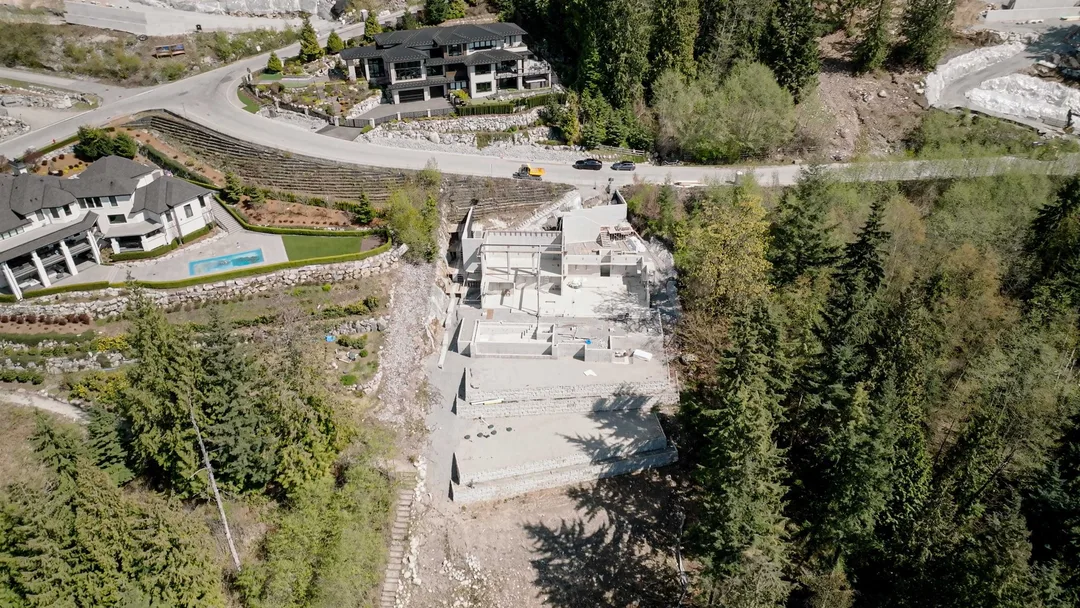 Chauhan Anmore — hillside aerial of active jobsite among trees and neighbouring homes